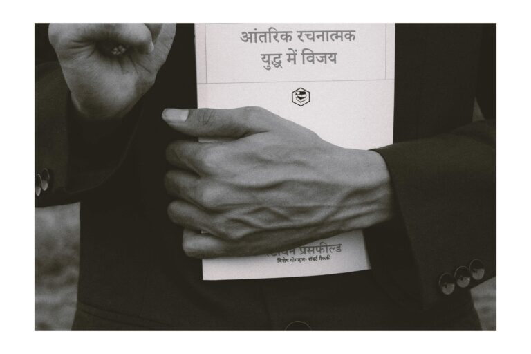 Hand of a person holding a hindi language book.